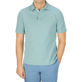 A man wearing a Fedeli washed light green cotton pique polo shirt and blue pants.