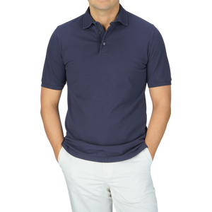 A man wearing a Fedeli Washed Navy Cotton Pique Polo Shirt and white pants.