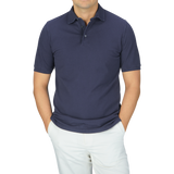 A man wearing a Fedeli Washed Navy Cotton Pique Polo Shirt and white pants.