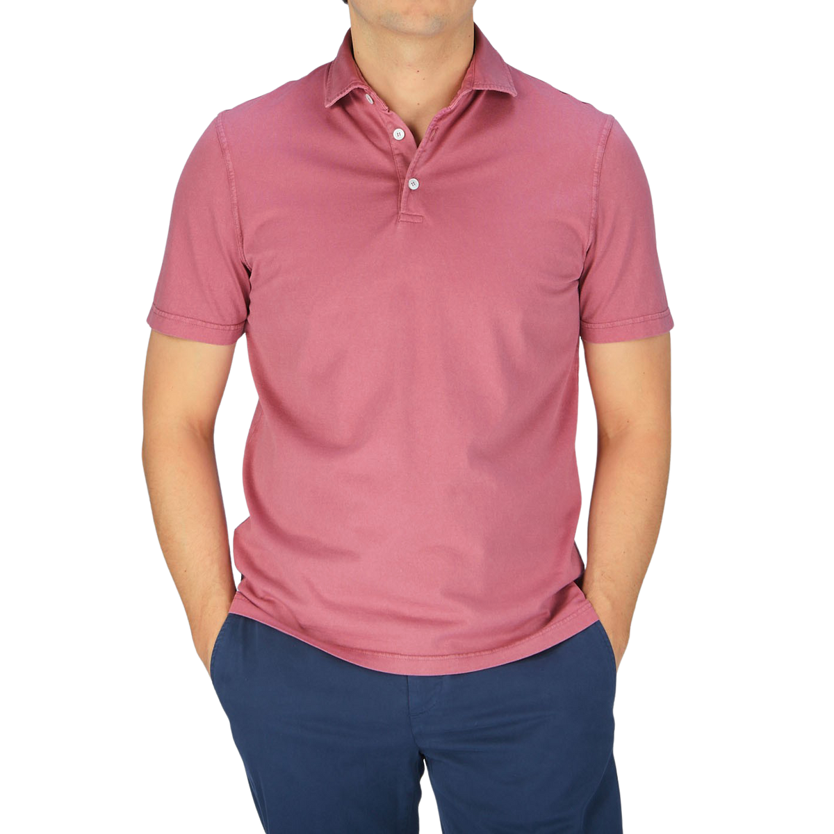A man wearing a Fedeli washed raspberry organic cotton polo shirt and blue pants.