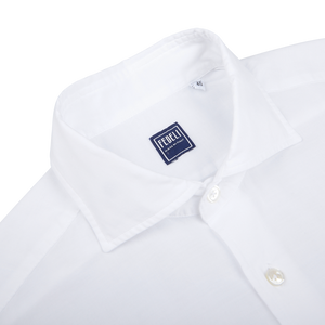 Close-up of a Fedeli white cotton stretch beach shirt with a label showing the brand name.