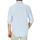 The back view of a man wearing a handmade Finamore Sky Blue Striped Cotton Seersucker Shirt and khaki pants.