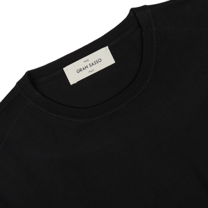 Close-up view of a black organic cotton t-shirt's neckline showing a "Gran Sasso" brand label on a white tag.