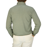 The back view of a man wearing a Gran Sasso Grass Green Vintage Merino Wool 1/4 Zip Sweater and white pants.
