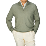 A man wearing a Gran Sasso Grass Green Vintage Merino Wool 1/4 Zip Sweater and white pants, exuding a vintage feel.