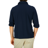 Person wearing a Gran Sasso navy blue slim fit polo shirt, made from cotton jersey and paired with light beige trousers, viewed from the back.