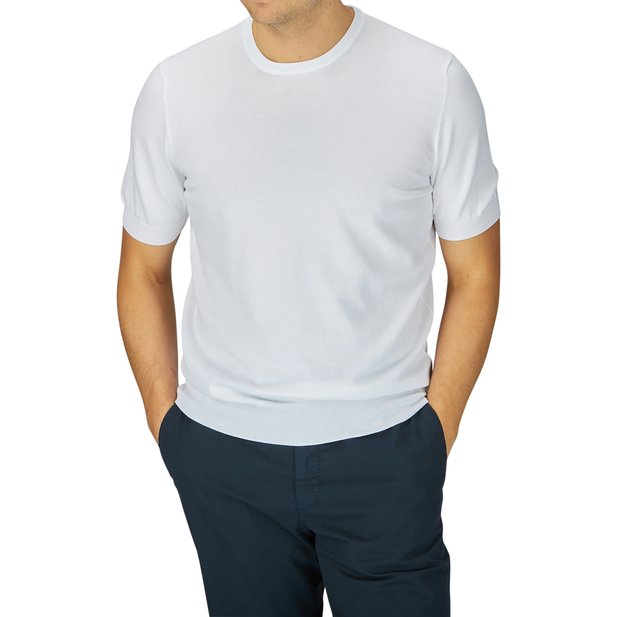 A man wearing a Gran Sasso white organic cotton knitted t-shirt and navy blue pants, standing with his arms slightly away from his sides.