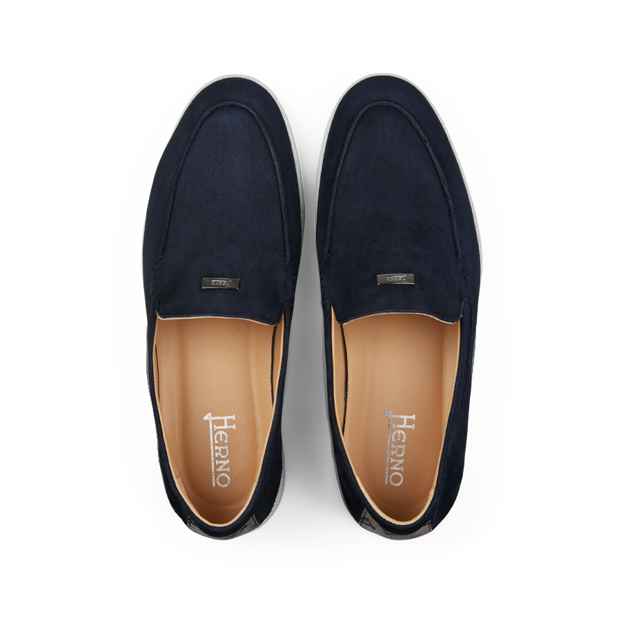 A pair of Herno dark blue suede slip-on loafers with a tan interior, displayed on a black background.