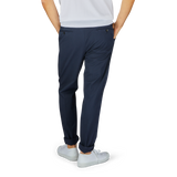 A person standing against a gray background showcasing Incotex navy blue cotton stretch regular fit chinos paired with white sneakers.