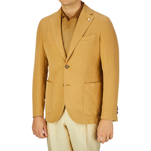 A man wearing a L.B.M. 1911 Dark Beige Washed Cotton Linen Blazer with a lapel pin over a light-colored shirt, paired with cream pants.