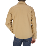 The back view of a man wearing a Camel Beige Cotton Ripstop Country Overshirt by Manifattura Ceccarelli.