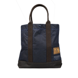 A Navy Blue waxed cotton tote bag with brown handles by Manifattura Ceccarelli.