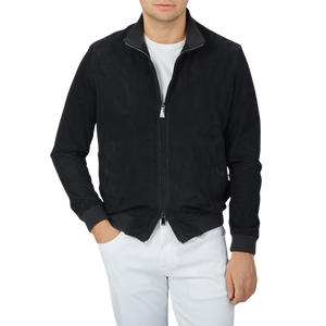 A man wearing a luxurious Manto Navy Blue Perforated Suede Leather Blouson jacket and white pants.