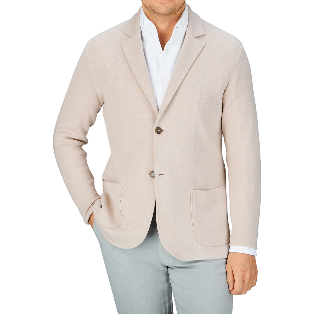 Man in a Maurizio Baldassari light beige silk cotton knitted Milano blazer and light grey pants with a white shirt unbuttoned at the collar, offering a casual substitute to formal wear.