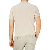 The back view of a man wearing a lightweight Mauro Ottaviani cream beige cotton silk polo shirt and khaki pants.