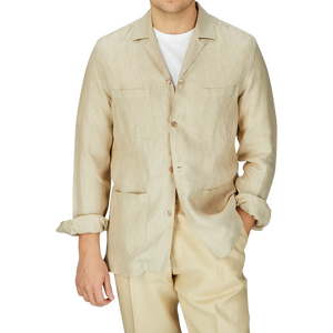 Man in a Khaki Beige Organic Linen Four Pocket Overshirt and matching pants by Mazzarelli, with a white t-shirt underneath, standing against a gray background.