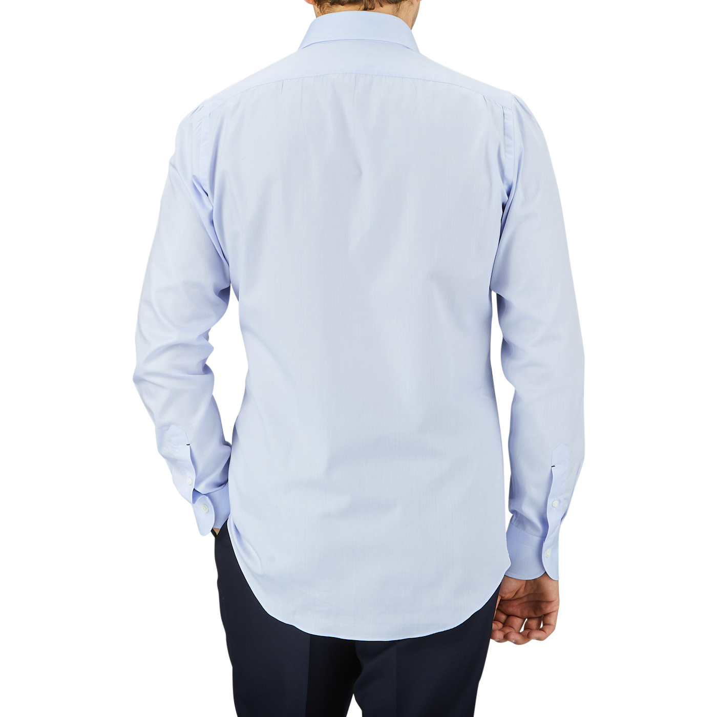 A man seen from behind, wearing a light blue Mazzarelli Light Blue Slim Cutaway Herringbone Shirt and dark trousers, standing against a grey background.