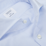 Close-up of a Light Blue Slim Cutaway Herringbone Shirt by Mazzarelli with a visible label reading "Mazzarelli Camicia Uomo, Made in Italy" and two white buttons.