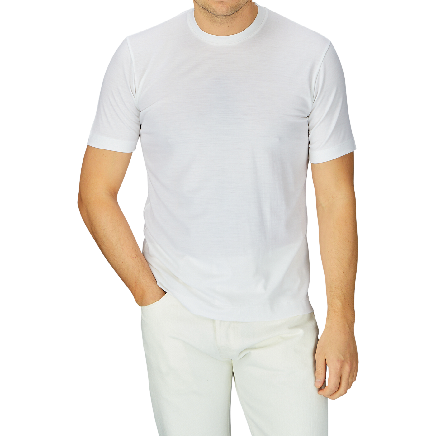 Man in a breathable Off-White Merino Wool T-shirt from Mazzarelli and light beige pants, standing with one hand partially in his pocket against a grey background.