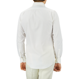 Rear view of a man wearing an Off White Cotton Twill BD Slim Shirt by Mazzarelli and light green pants, standing against a gray background.