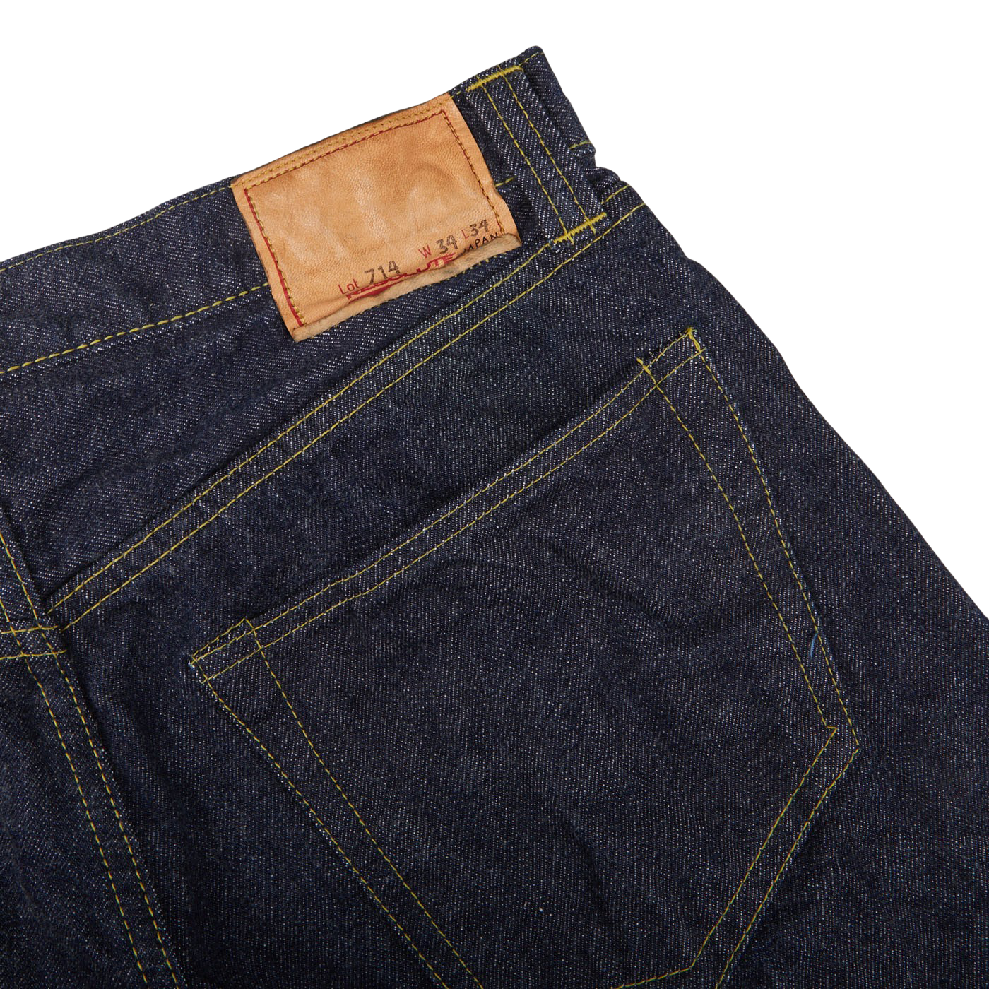 Close-up of the back pocket of Resolute's Dark Blue Cotton 714 One Wash Jeans featuring yellow stitching and a brown leather brand patch.