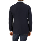 Rear view of a man wearing a Ring Jacket Navy Blue Wool Balloon Travel Blazer and jeans, standing against a light grey background.