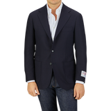 Man wearing a Ring Jacket Navy Blue Wool Balloon Travel Blazer over a white shirt paired with jeans, standing against a gray background.