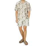 A man in a Sunspel Ecru Katie Scott Printed Resort Shirt and sandals.