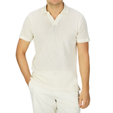 A man wearing a Sunspel Ecru White Linear Cotton Mesh Polo Shirt made of Supima cotton and pants.