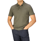 A man wearing a Khaki Green Cotton Riviera Polo Shirt by Sunspel and jeans.