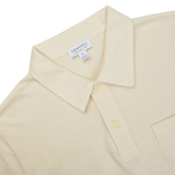 A beige Sunspel Undyed Cotton Riviera Polo Shirt with a pocket, perfect for channeling James Bond vibes.