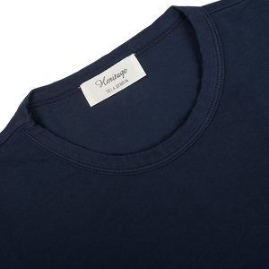 Close-up of a Navy Blue Heavy Organic Cotton T-Shirt's label with the brand "Tela Genova" and textile information "100% cotton.