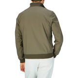 Man wearing an olive green cotton ripstop Valstar jacket with a ribbed collar and white trousers, viewed from the back.