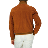 Man wearing an Italian Sandal Brown Suede Leather Valstarino jacket and white pants, seen from the back.