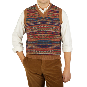 A man sporting a William Lockie Light Brown Fair Isle V-Neck Lambswool Slipover with a vibrant and colorful pattern made of Scottish lambswool.