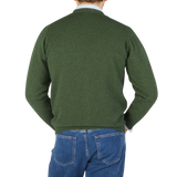 The back view of a man wearing a William Lockie Rosemary Green Lambswool Saddle Shoulder Cardigan.