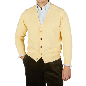 A man wearing a William Lockie Solar Yellow Lambswool Saddle Shoulder Cardigan.