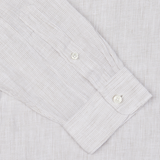 A close-up of a beige striped casual shirt cuff with two buttons from Xacus.