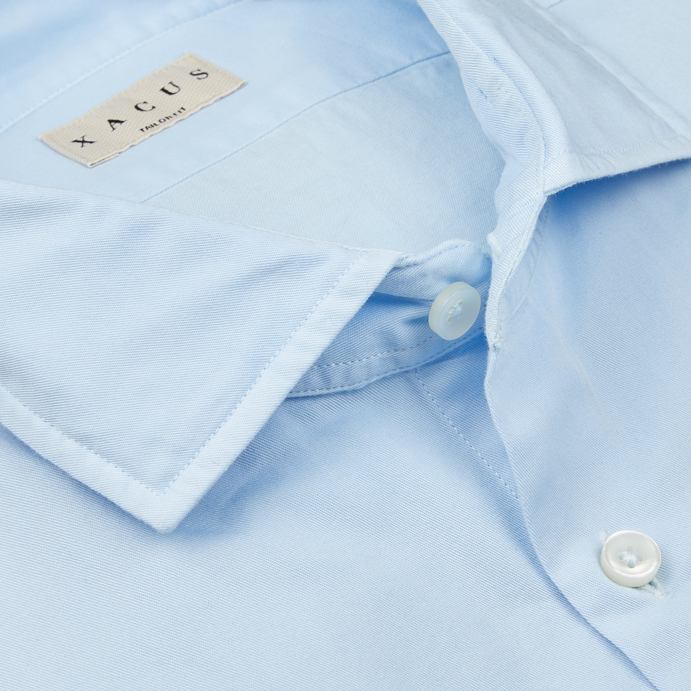 Close-up of a pure cotton Light Blue Cotton Twill Tailor Fit Shirt with a white button and a collar label that reads 'Xacus'.