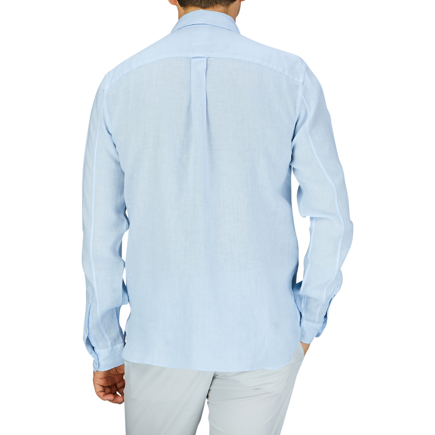 A man standing with his back to the camera wearing a Xacus Light Blue Washed Linen Legacy Shirt and light-colored pants.