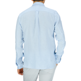 A man standing with his back to the camera wearing a Xacus Light Blue Washed Linen Legacy Shirt and light-colored pants.