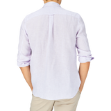A man seen from the back wearing a light Lilac Striped Washed Linen Legacy shirt with rolled-up sleeves and beige pants by Xacus.