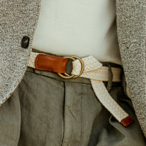 A man is wearing the Cream Beige Cotton Canvas 30mm Belt by Anderson's with a ring on it.