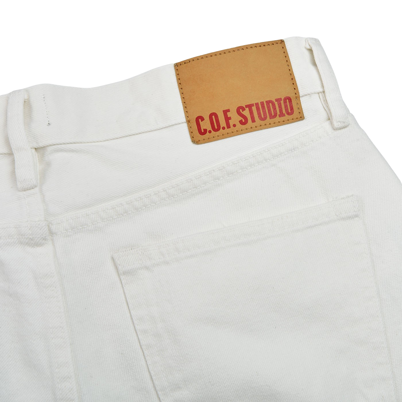 A pair of Ecru Stone Washed Kuroki Cotton M7 jeans with a label that says C.O.F Studio made from Kuroki organic denim.