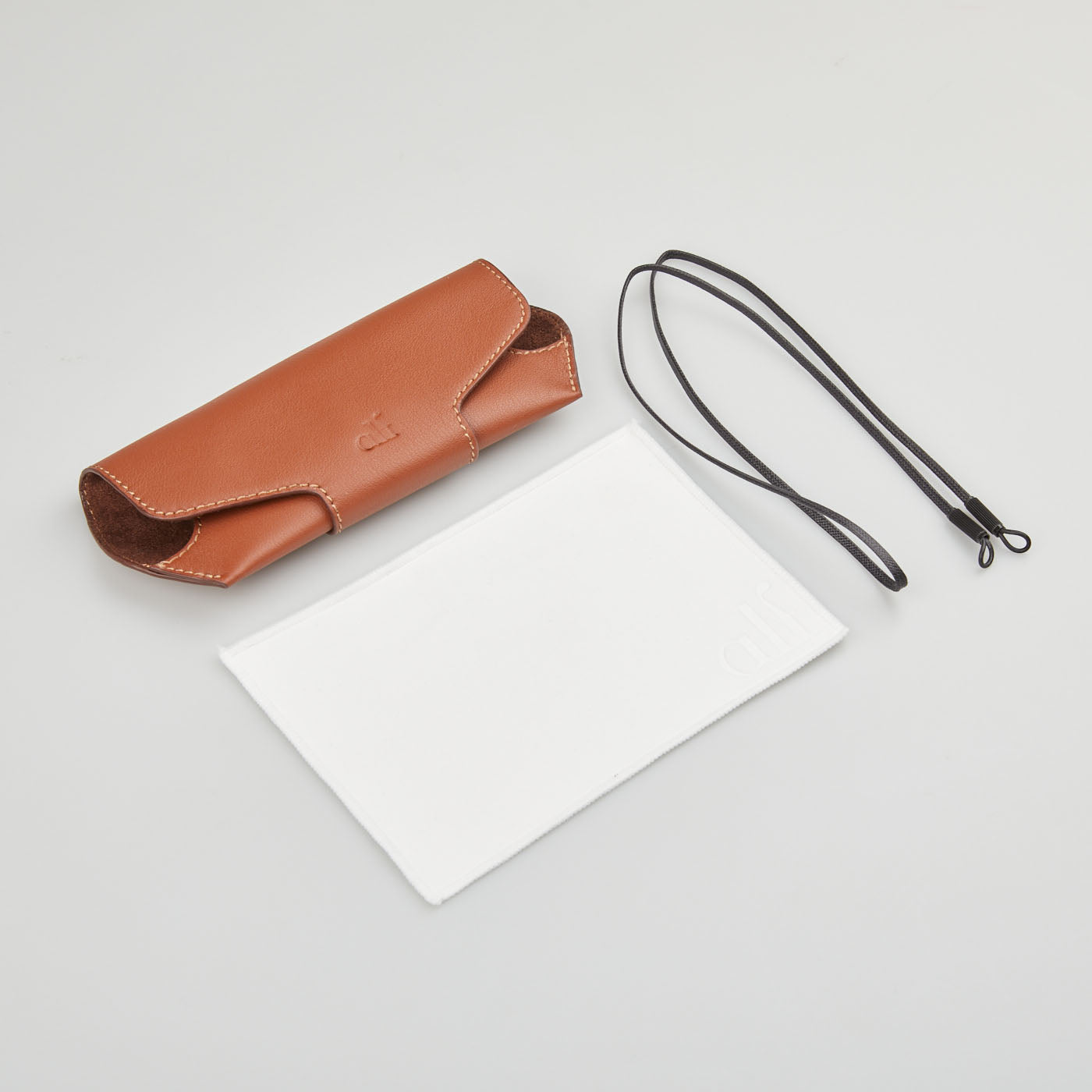 A rectangular brown leather case with a notepad and paper, containing the Black A22.13.001 Sunglasses by Lunettes Alf.