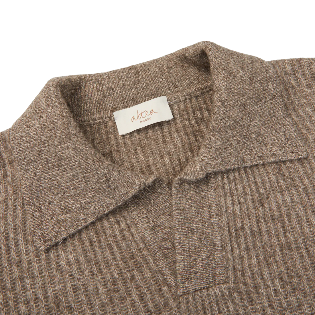 Close-up of a beige knitted sweater with a visible brand label on the collar.