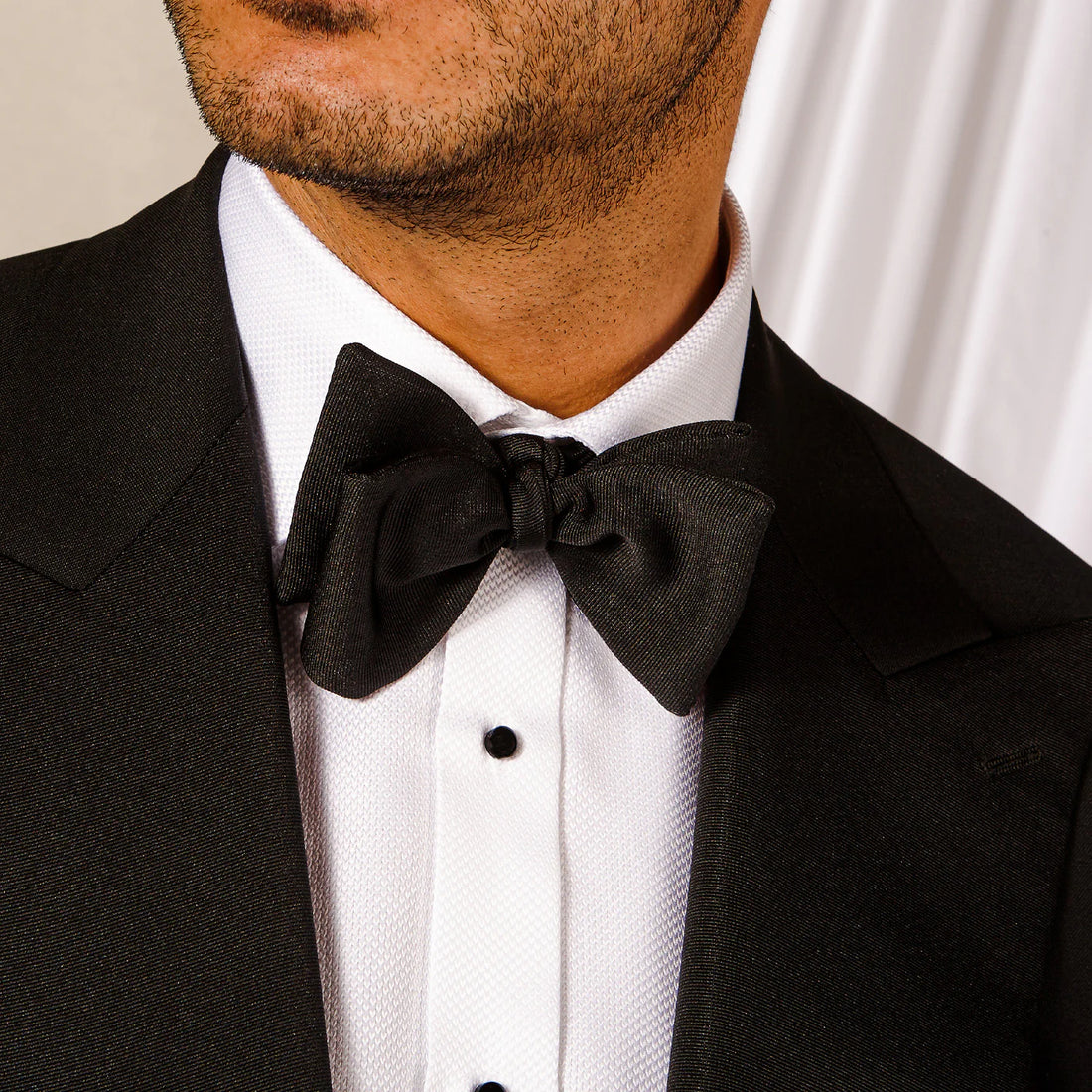 Close-up of a man in a black tuxedo with a white shirt and a black bow tie.