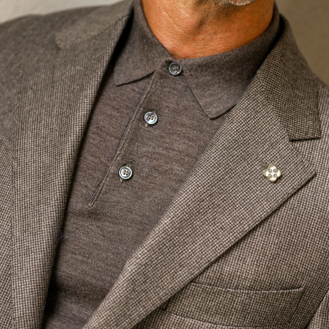 Cropped photo of a person wearing a beige shirt over a white undershirt.