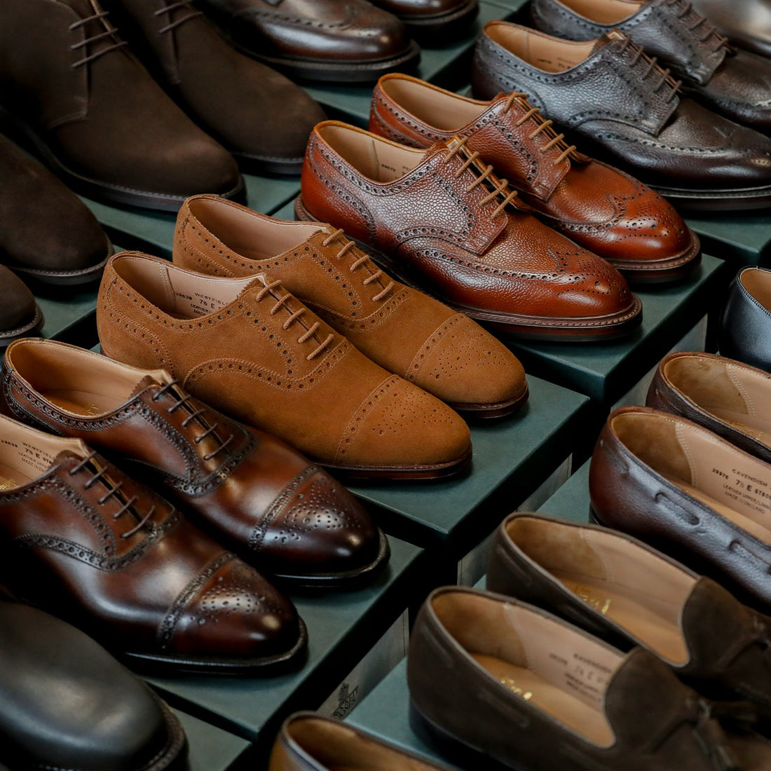 A display of assorted men's dress shoes, including brogues and loafers, in various shades of brown and black.