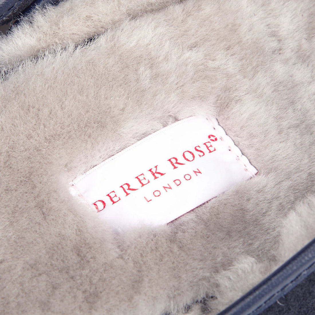 Close-up of a "derek rose london" label on a garment with a soft, fur-like lining.